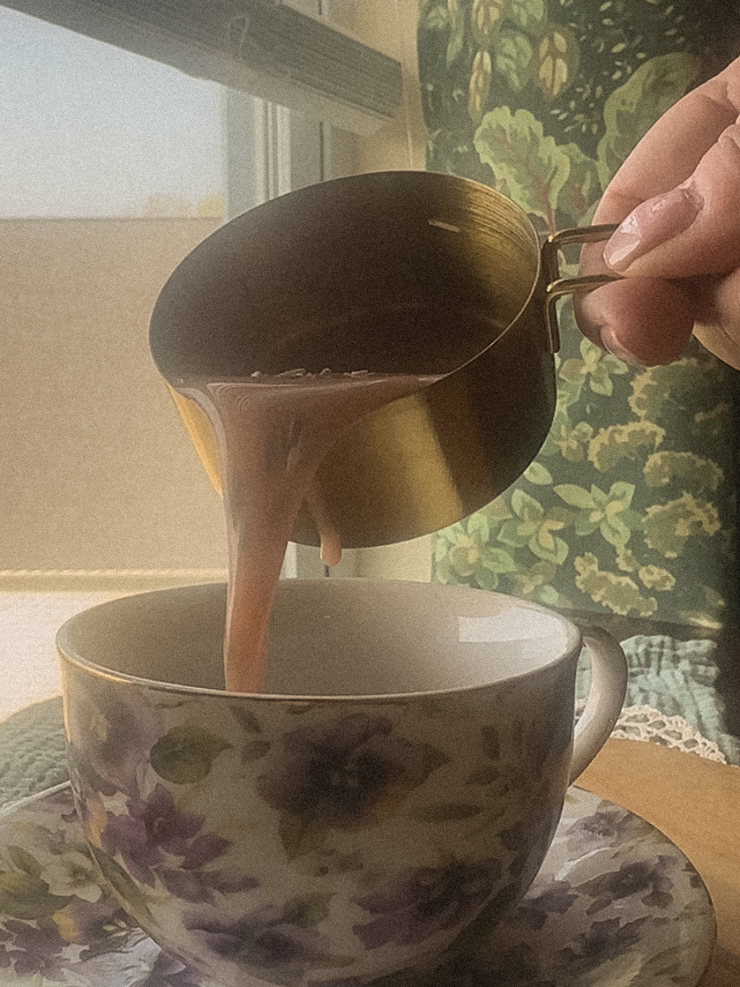 Creamy herbal moon milk being poured into a cottagecore mug with a frothy top in warm, cozy lighting